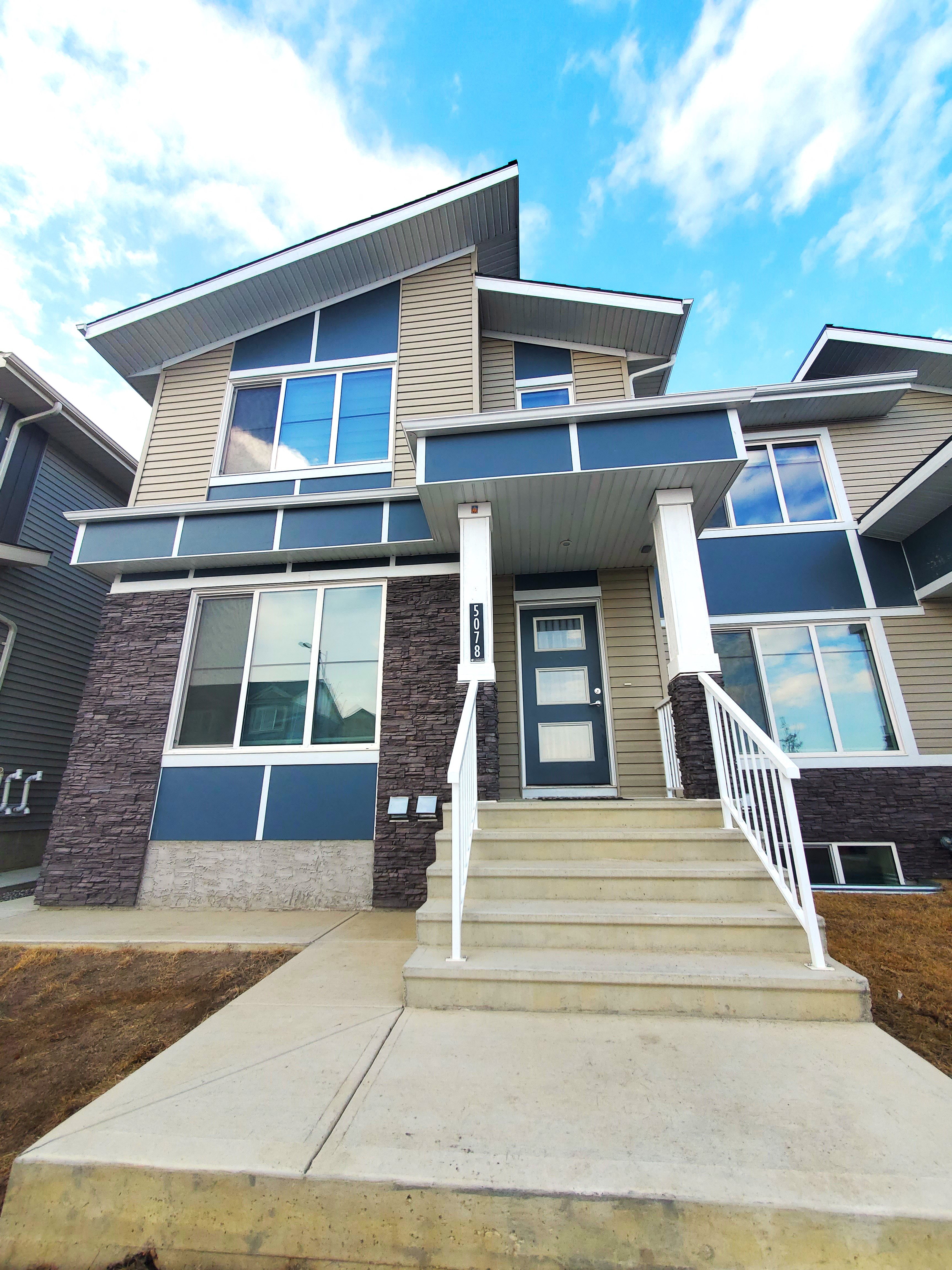 A modern house with a front porch and stairs leading to the entrance.